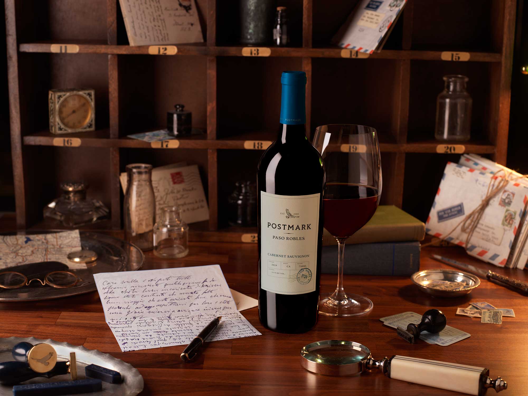 Postmark Wine Bottle and Glass of Paso Cabernet Sauvignon on Desk
